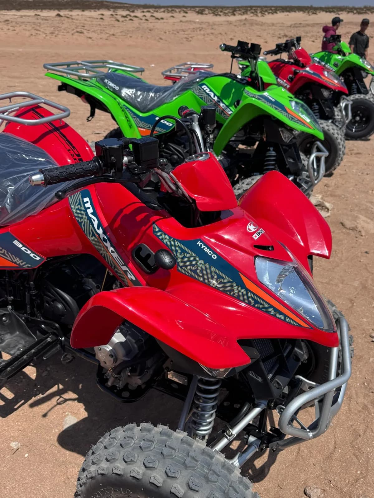 Quads rojos y verdes alineados sobre la arena antes de salir.