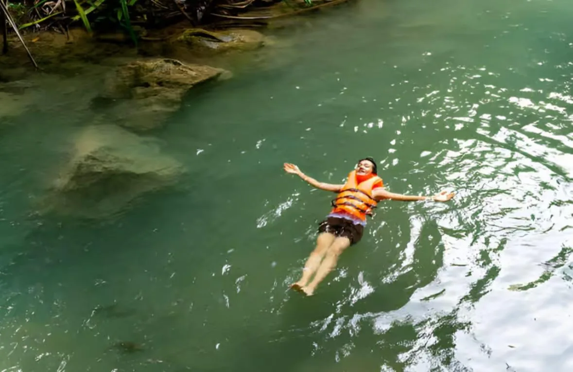 Una bañista flotando de espaldas en una de las pozas naturales verdes.