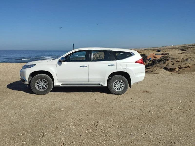 Un 4x4 blanc garé sur le sable au-dessus de l'océan, à Tifnit.